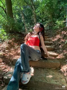 a woman sitting on steps in the woods with her eyes closed and headphones up to her ear