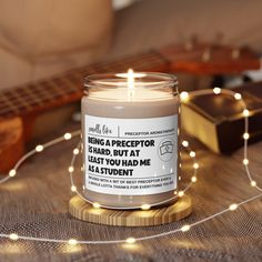 a lit candle sitting on top of a wooden table next to a string of lights