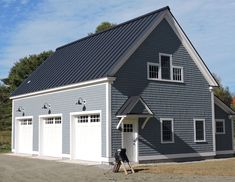 a gray two story garage with white doors and windows