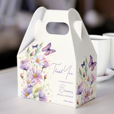 a white box sitting on top of a table next to two cups and saucers