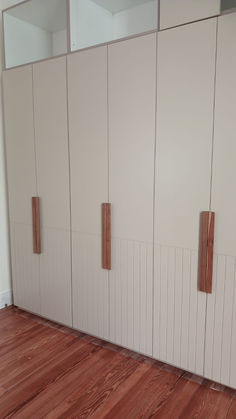 an empty room with wooden floors and white cabinets on the wall, in front of a wood floor