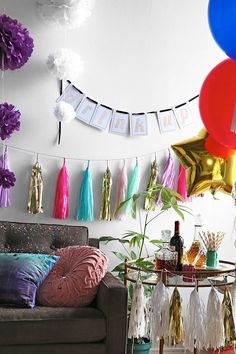 balloons and streamers are hanging from the ceiling above a couch in a room filled with party decorations