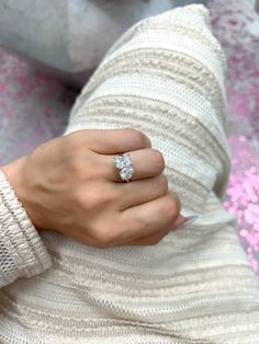 a woman's hand with a diamond ring on her left wrist, wearing a white sweater