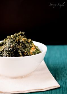 a white bowl filled with green vegetables on top of a tablecloth next to a napkin