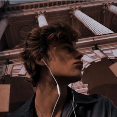 a young man listening to headphones in front of a building with columns and pillars