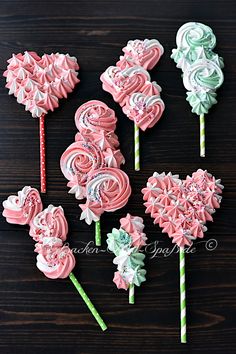 pink and green lollipops are arranged on a wooden table with candy canes