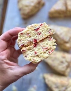 a person holding up a biscuit with cranberries on it