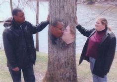 two people are standing next to a tree and one is touching the other's face