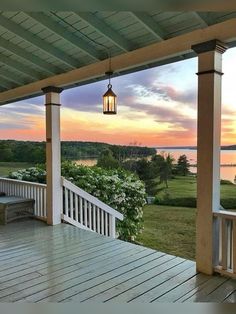 a porch with a light hanging from it's ceiling and a view of the water