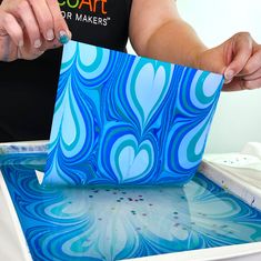 a person is cutting out some paper with scissors and glue on the edge of an art project