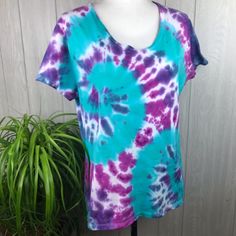 a blue and purple tie - dye shirt on a mannequin dummy next to a potted plant