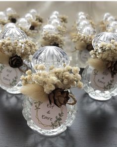 small glass vases filled with dried flowers on top of a black tablecloth covered table