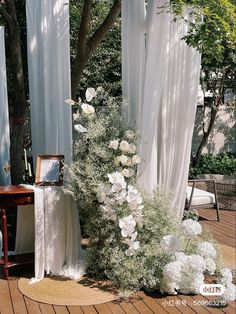 an outdoor ceremony setup with white flowers and greenery on the ground, surrounded by drapes