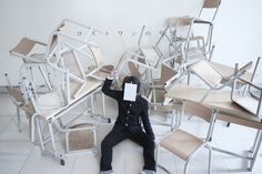 a person sitting on the ground in front of many chairs with paper taped to their faces