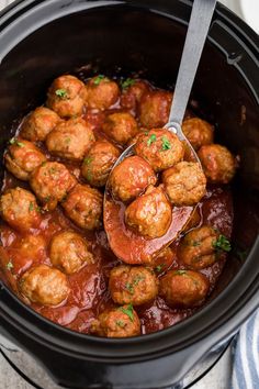 a ladle scooping some meatballs out of the crock pot with sauce