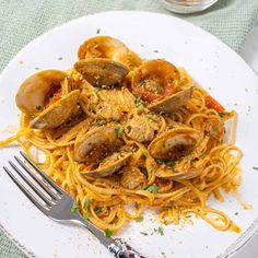 pasta with clams and parmesan cheese on a plate next to a fork