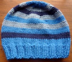 a blue and gray knitted hat sitting on top of a wooden table