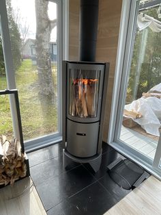 a wood burning stove sitting inside of a living room next to a large window with glass doors