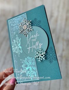 a hand holding up a card with snowflakes on it and the words deck the hall