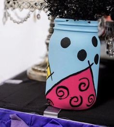 a blue jar with flowers in it sitting on a table next to a purple cloth