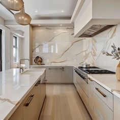 a modern kitchen with marble counter tops and white cabinets, along with wooden flooring