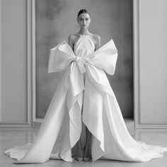 a woman in a white dress with large bow on her back