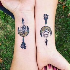 two people with matching tattoos on their arms, one has an arrow and the other has a compass