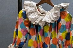 a colorful polka dot blouse hanging on a clothes rack