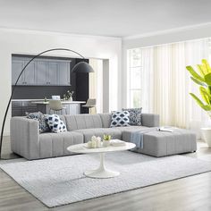 a living room filled with furniture next to a large white floor rug on top of a hard wood floor