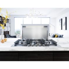 a stove top oven sitting inside of a kitchen next to a table with yellow flowers on it