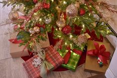 a christmas tree with presents under it in front of a pile of wrapped gift boxes