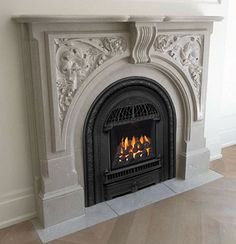 a fire place in the middle of a room with wood flooring and white walls