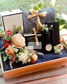 an arrangement of flowers, watches and jewelry on a wooden tray with a blue pillow