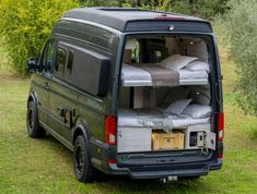 the back end of a van with beds in it's cargo compartment, parked on grass