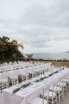 tables set up with white linens and greenery for an outdoor wedding reception at the beach