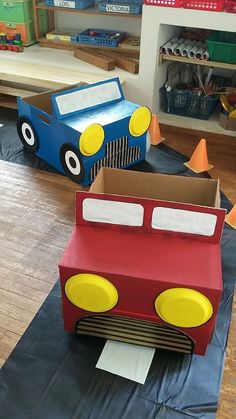 there is a cardboard firetruck and truck on the floor in this playroom