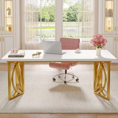 a desk with a laptop on it in front of a window and pink chair next to it