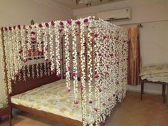 a bed covered in white and pink flowers next to a wall hanging from the ceiling