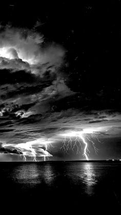 black and white photograph of lightning striking over the ocean