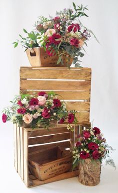 three wooden crates stacked on top of each other with flowers in them