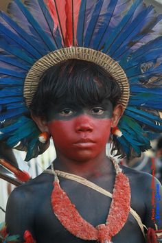 a young boy with blue and red feathers on his head