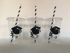 three plastic cups with black and white straws in them, decorated with graduation caps