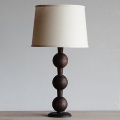 a wooden table lamp with a white shade on it's base and a beige linen lampshade