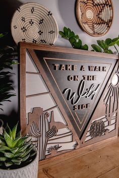 there is a sign that says take a walk on the wild side next to some succulents