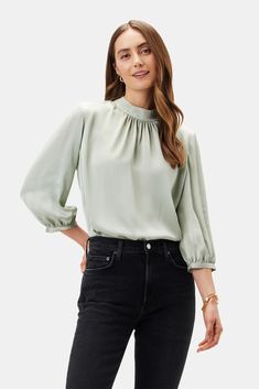 Sophisticated yet casually cool, our mock neck blouse gives just a hint of romance. Its elegant shirring and soft puff sleeves make it the ultimate day-to-night top. Mock neck, 3/4 puff sleeve blouse with shirring detail Keyhole slit with fabric-covered button at back of neck 100% Recycled Polyester 24" in length Ethic Green Blouse Outfit, Aesthetic Loungewear, Mint Green Blouses, Mom Wardrobe, Night Tops, Cotton Long Dress, Mock Neck Blouse, Fabric Covered Button, Puff Sleeve Blouse