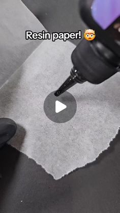 a person using a machine to cut paper on a piece of gray fabric with the words resin paper