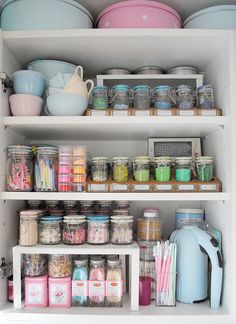 an open cabinet filled with lots of containers and bowls on top of it's shelves