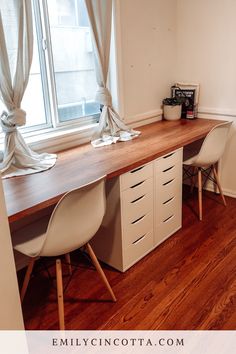 a desk with two white chairs and a window in the background, next to a wooden floor