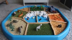 a play table filled with different types of animals and plants on top of sand in a living room