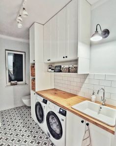 a washer and dryer in a white kitchen with black and white floor tiles